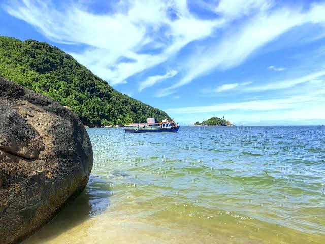 Praia de águas verdes com barco ancorado no Polo Sul
